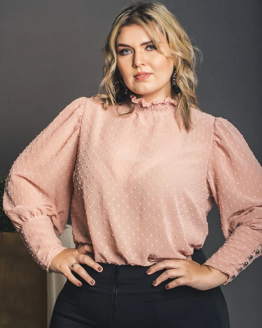 Shoulder-length blonde waves with soft part and pale blouse