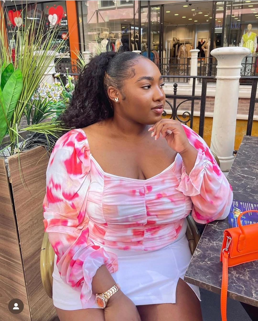 Curly ponytail with sleek pulled-back front and pink top