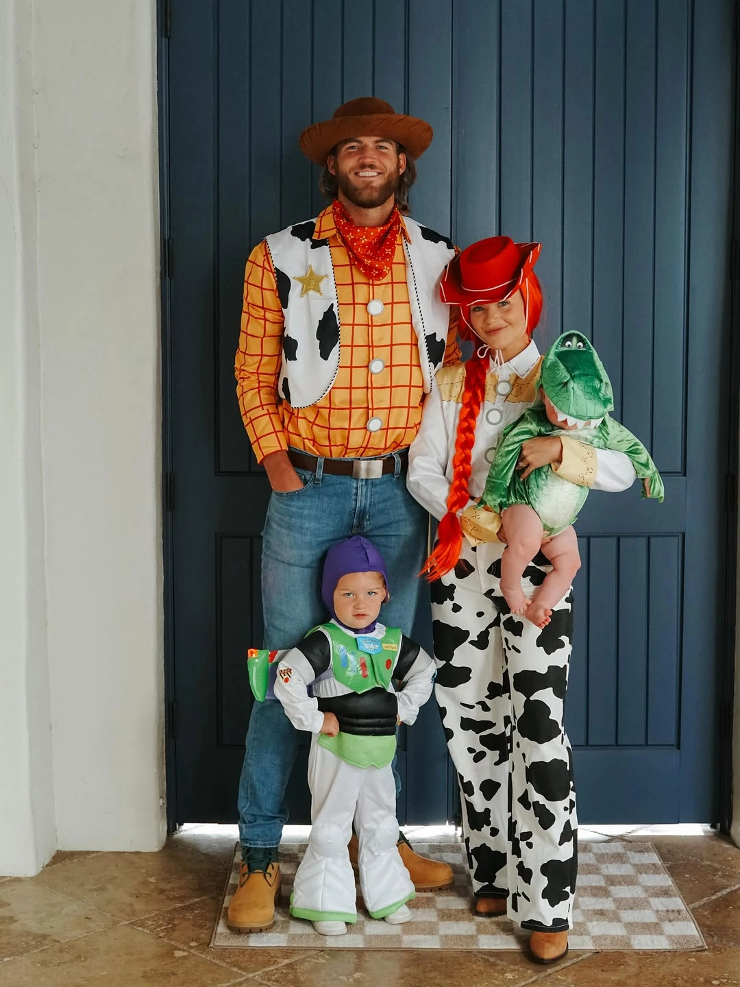 Family in cowboy cow-print and space-ranger-inspired Halloween costumes by a door