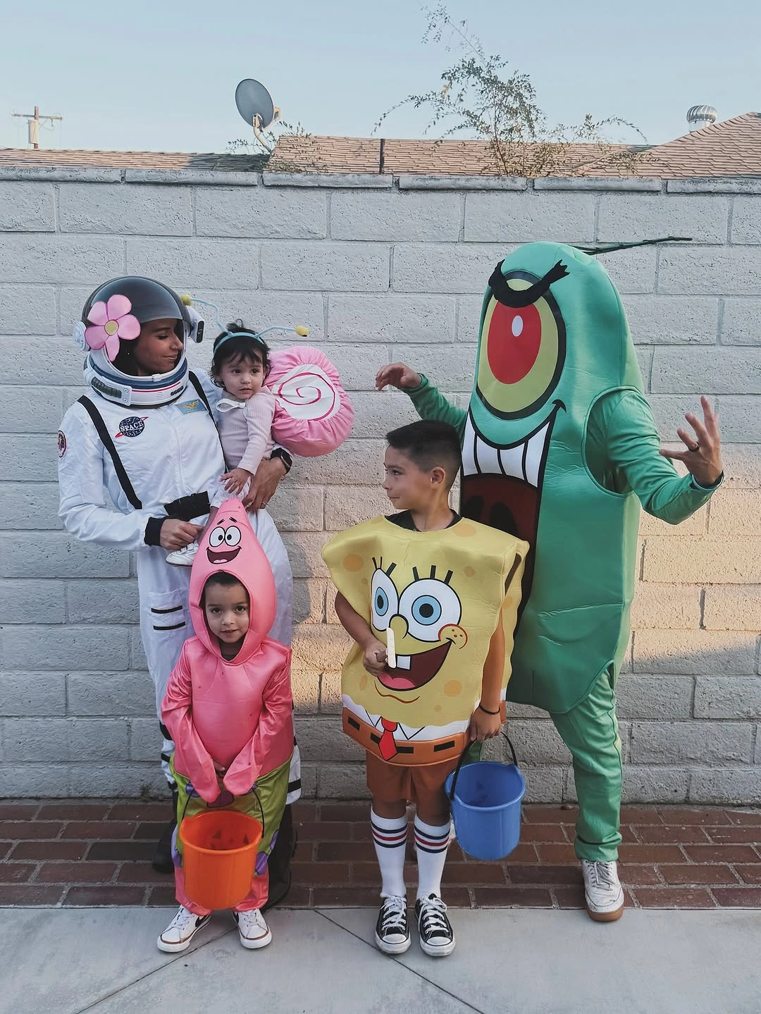 Five people in bright underwater cartoon-inspired Halloween costumes holding candy buckets
