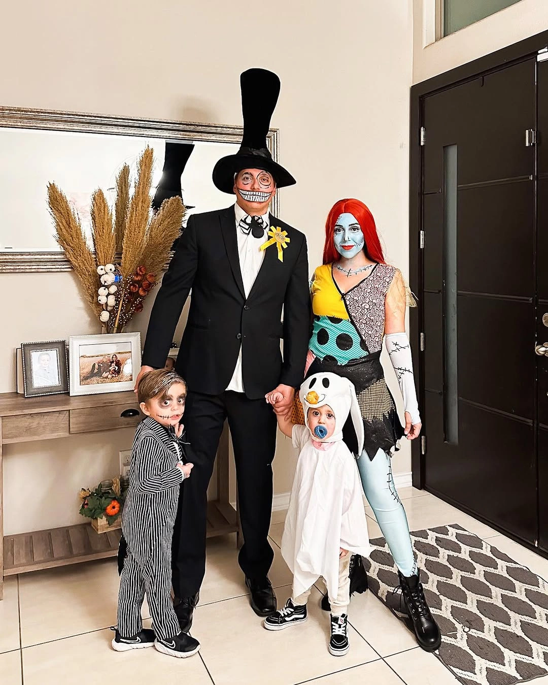 Family in formal black and patchwork Halloween costumes with a white ghost-costumed dog