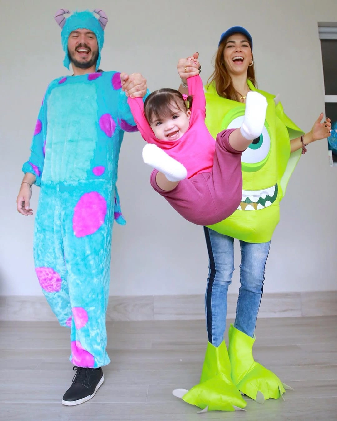 Two adults and a child in blue green and pink plush monster costumes