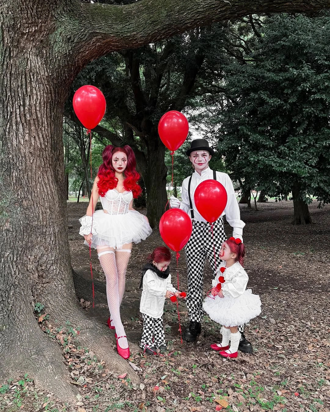 Family in red black and white carnival Halloween costumes with red balloons