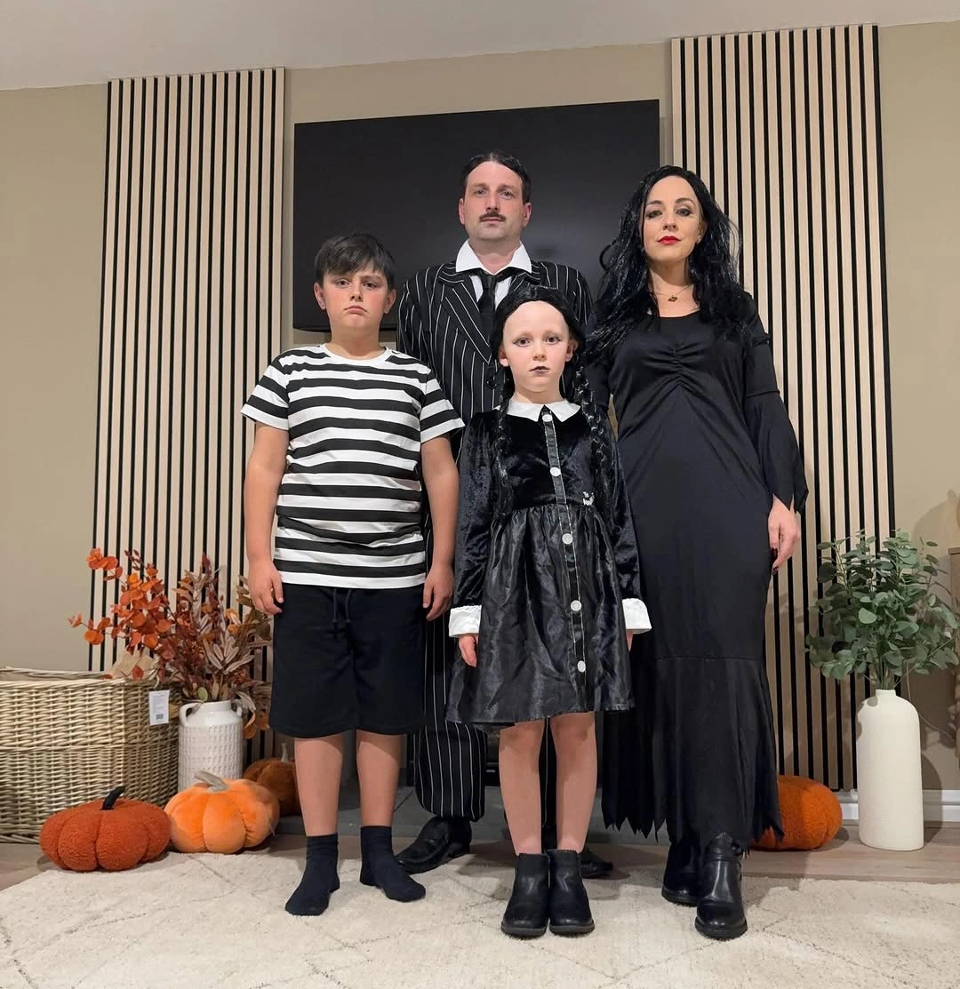 Family in black striped and gothic school-uniform-inspired Halloween outfits indoors