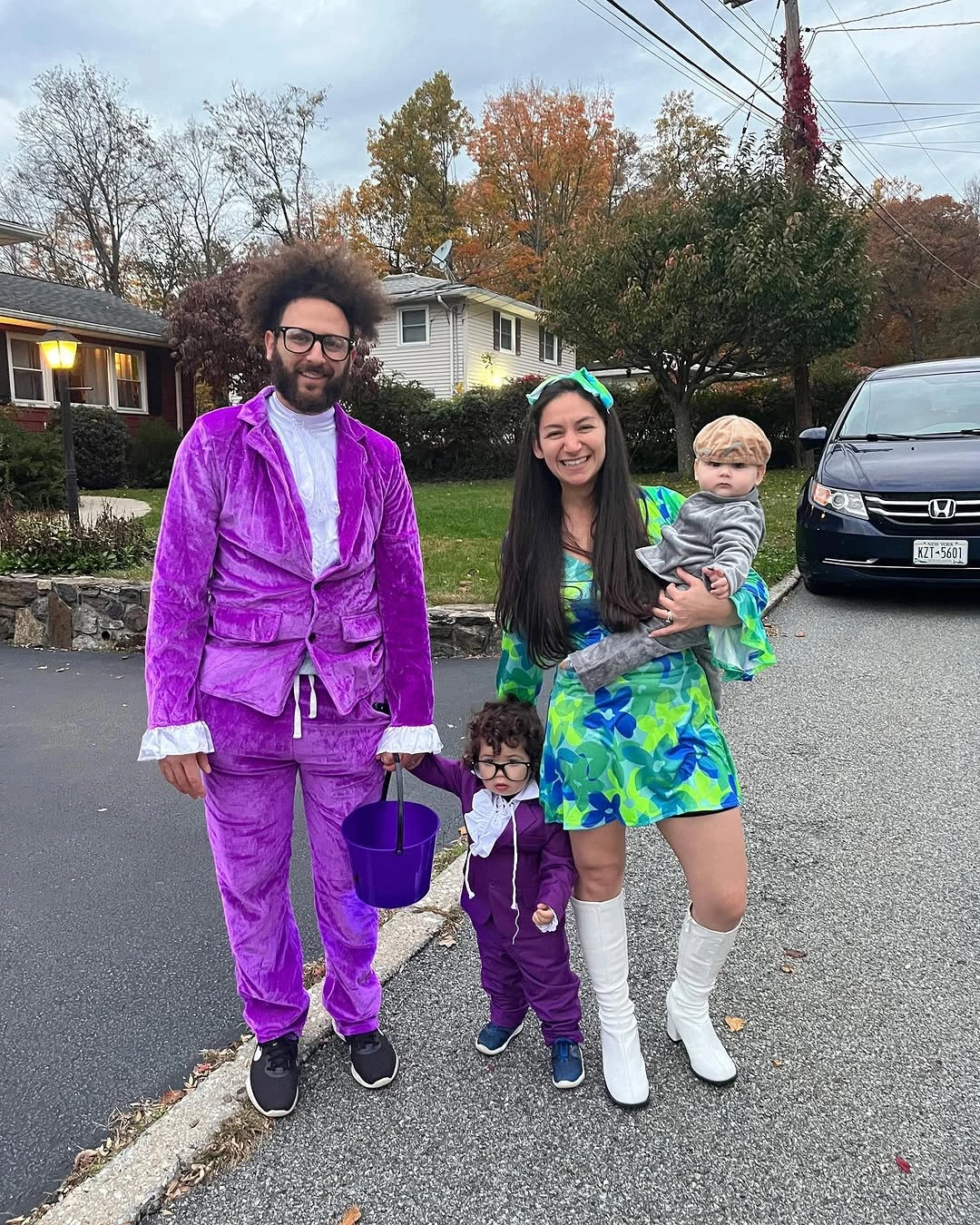 Family in purple suit green blue print and matching Halloween-inspired costumes outdoors