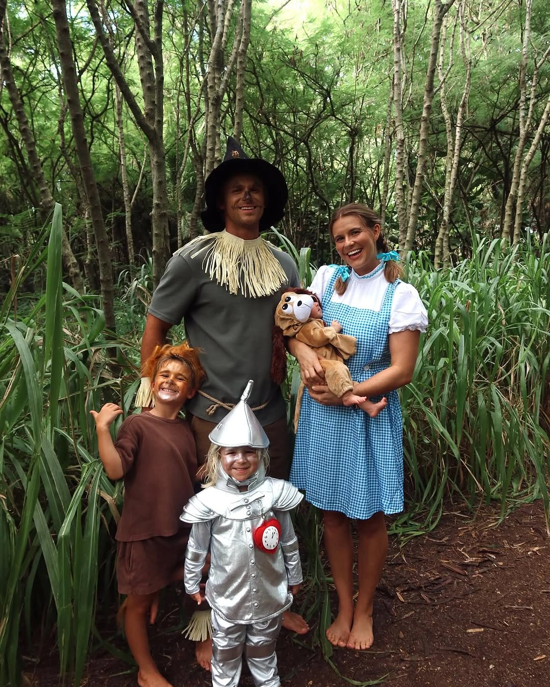 Family in scarecrow gingham lion and silver storybook Halloween costumes in a cornfield