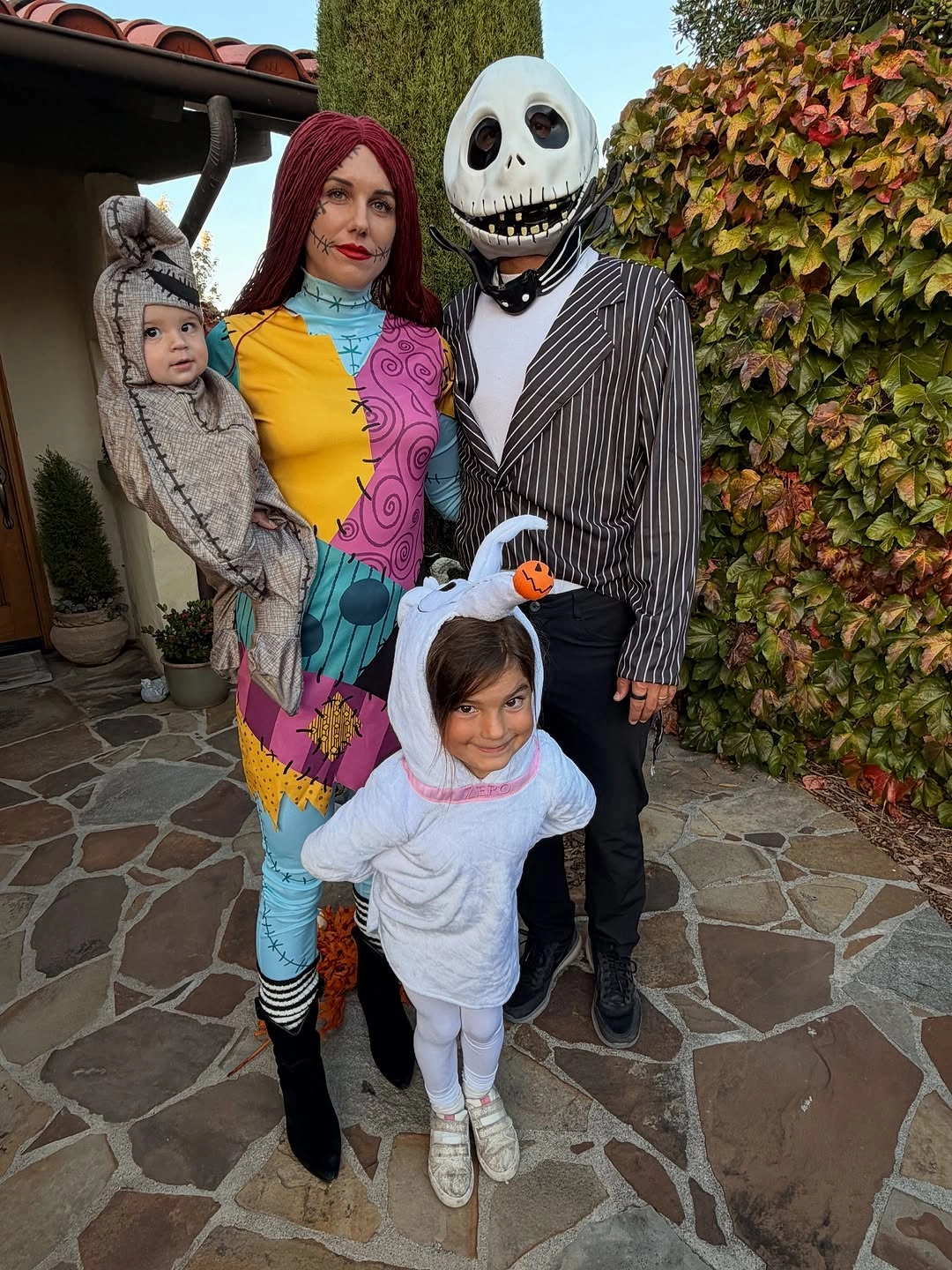 Family in striped skeleton patchwork and ghost Halloween costumes outdoors