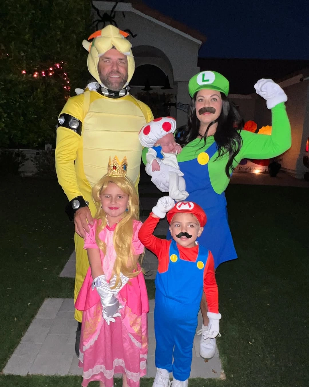 Family in yellow green pink red and blue game-inspired Halloween costumes at night