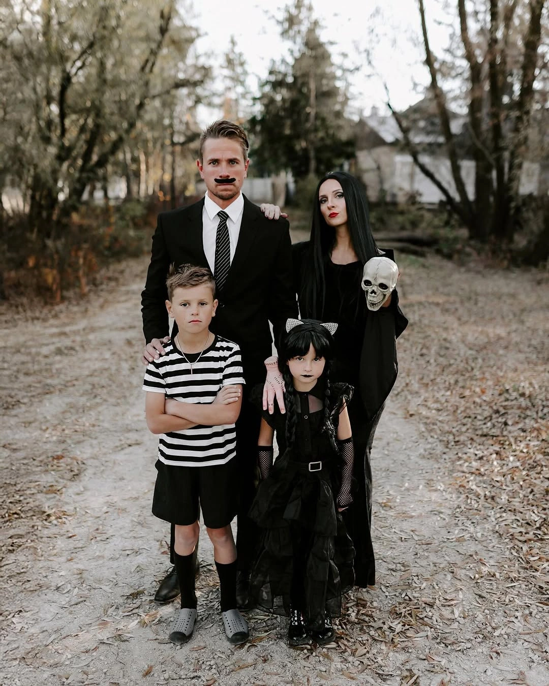 Family in black and white gothic Halloween outfits on a wooded path
