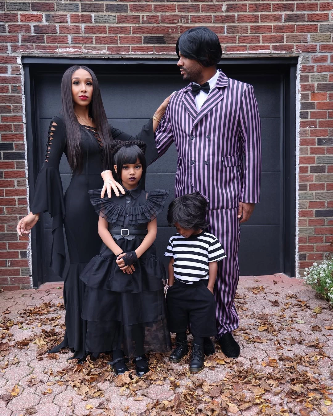Family wearing a pinstriped suit long black dresses and striped Halloween outfits