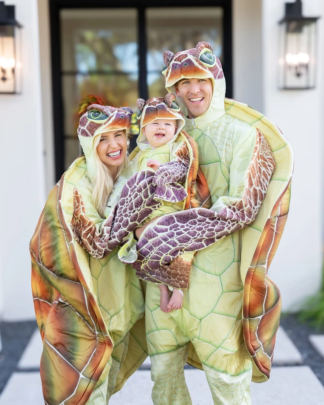 Parents and baby wearing green tan turtle-shell Halloween costumes