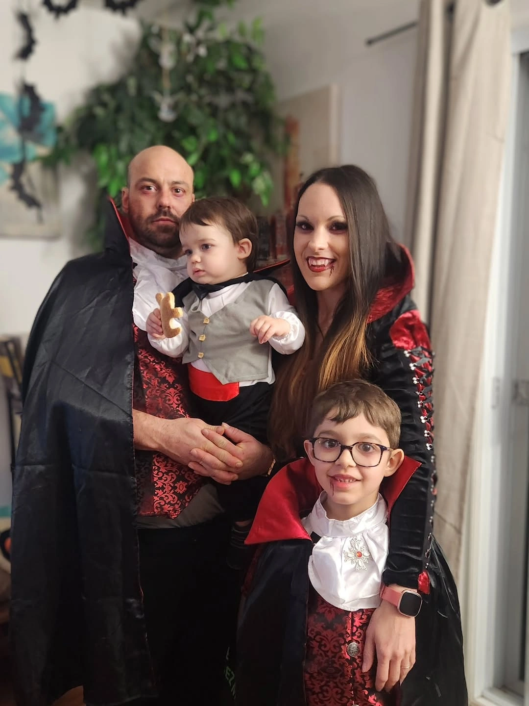 Family in black red and white vampire-inspired Halloween costumes indoors