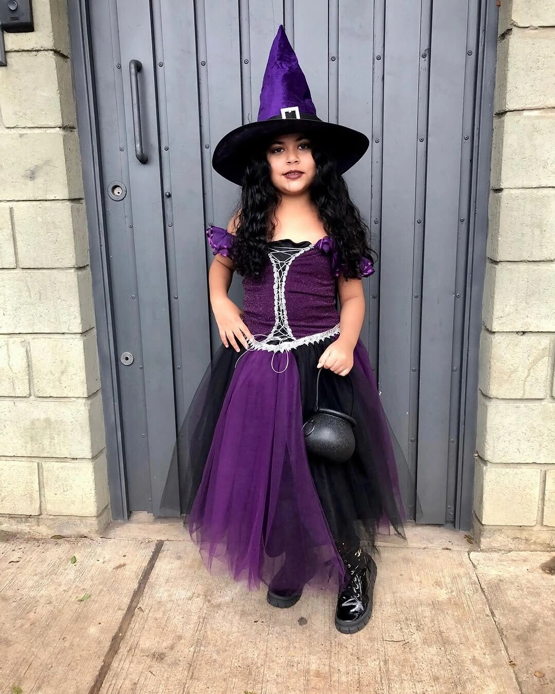 Girl in purple and black witch Halloween dress with pointed hat and tulle skirt