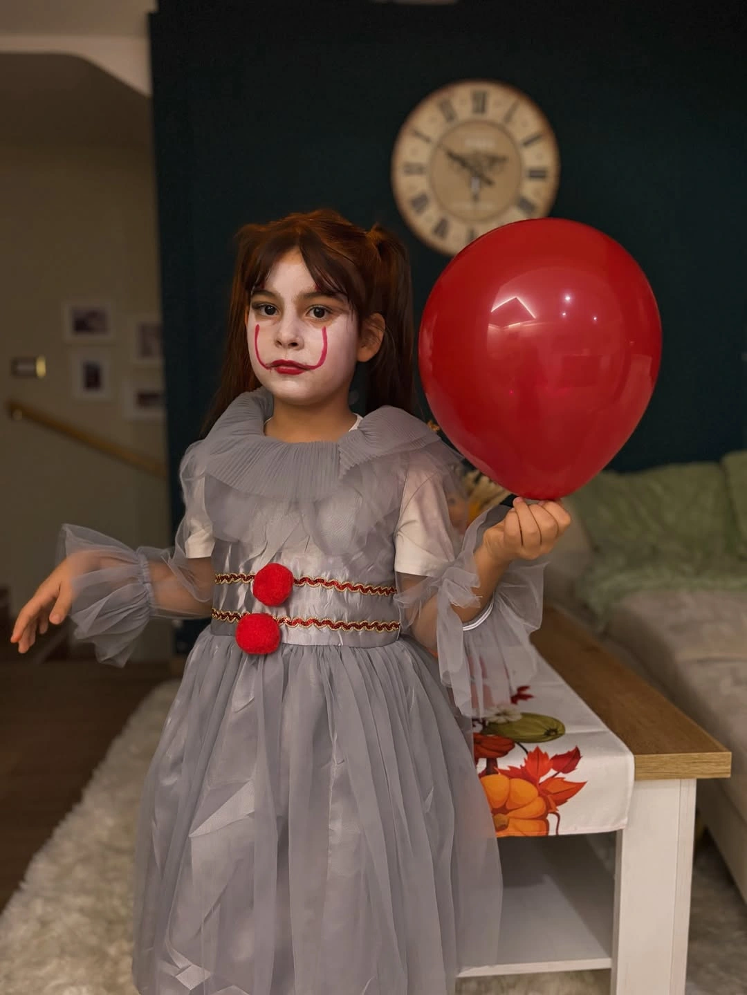 Girl in gray layered tulle Halloween dress with red pom-poms and red balloon