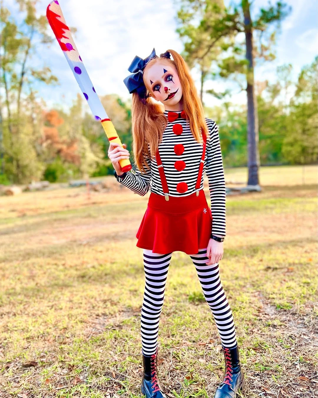 Girl in red pinafore striped sleeves tights and colorful circus Halloween styling