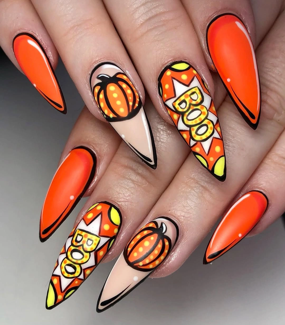 Long pointed orange nude and candy-corn nails with pumpkin and bold black lettering