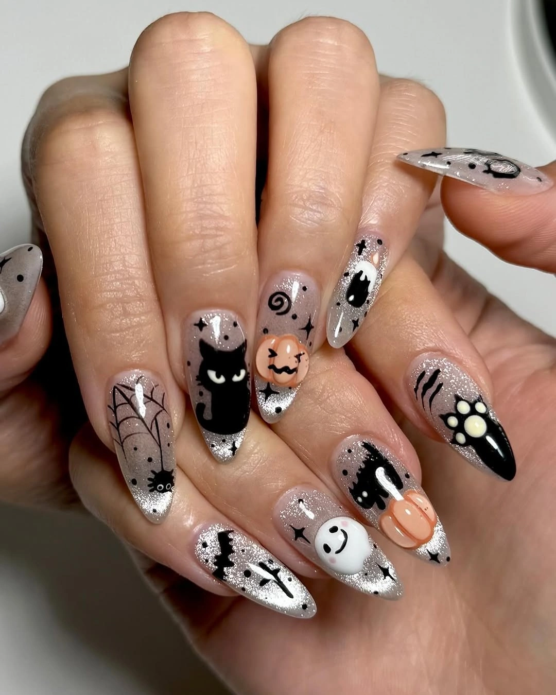 Long pointed black and white Halloween nails with cats pumpkins ghosts and webs
