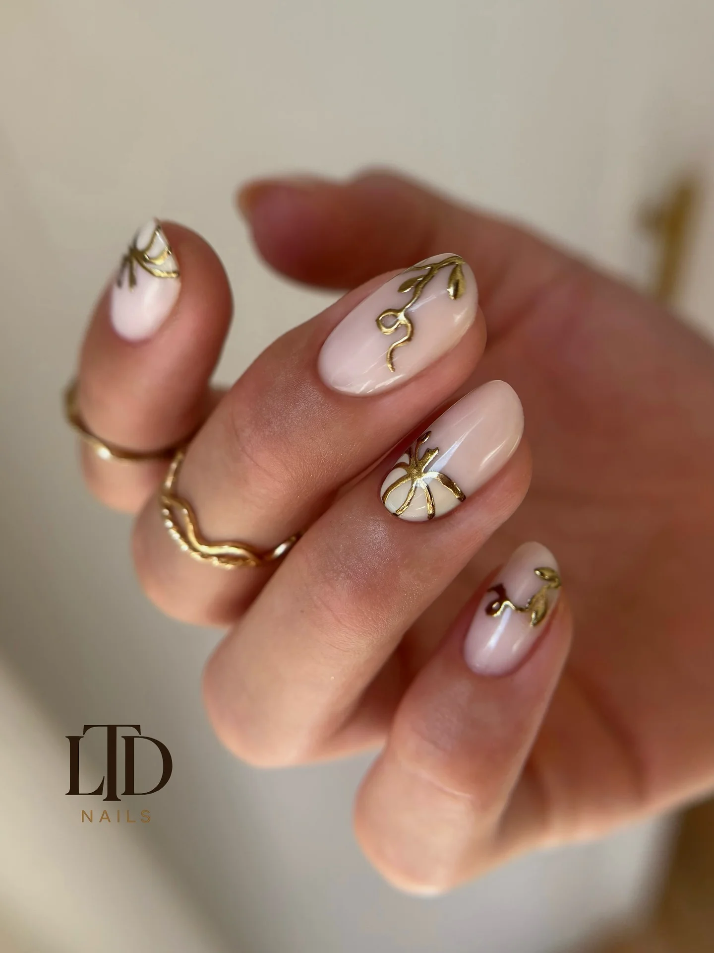 Short nude rounded nails with fine gold lines white and green Halloween details