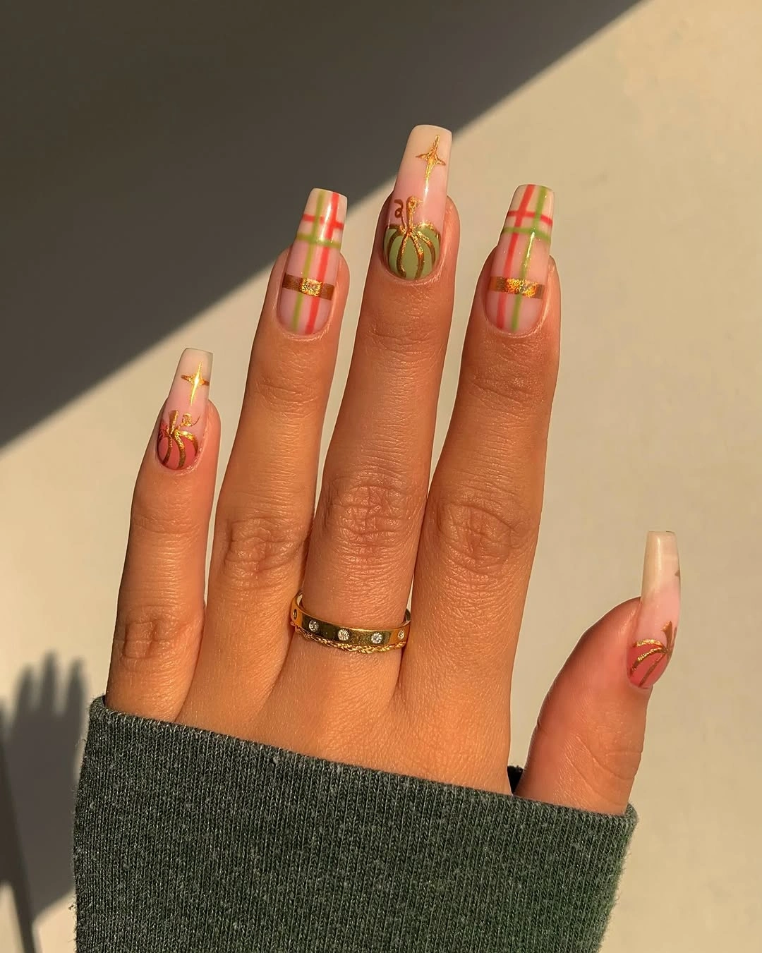 Long nude nails with orange pumpkins and narrow gold vertical stripe accents
