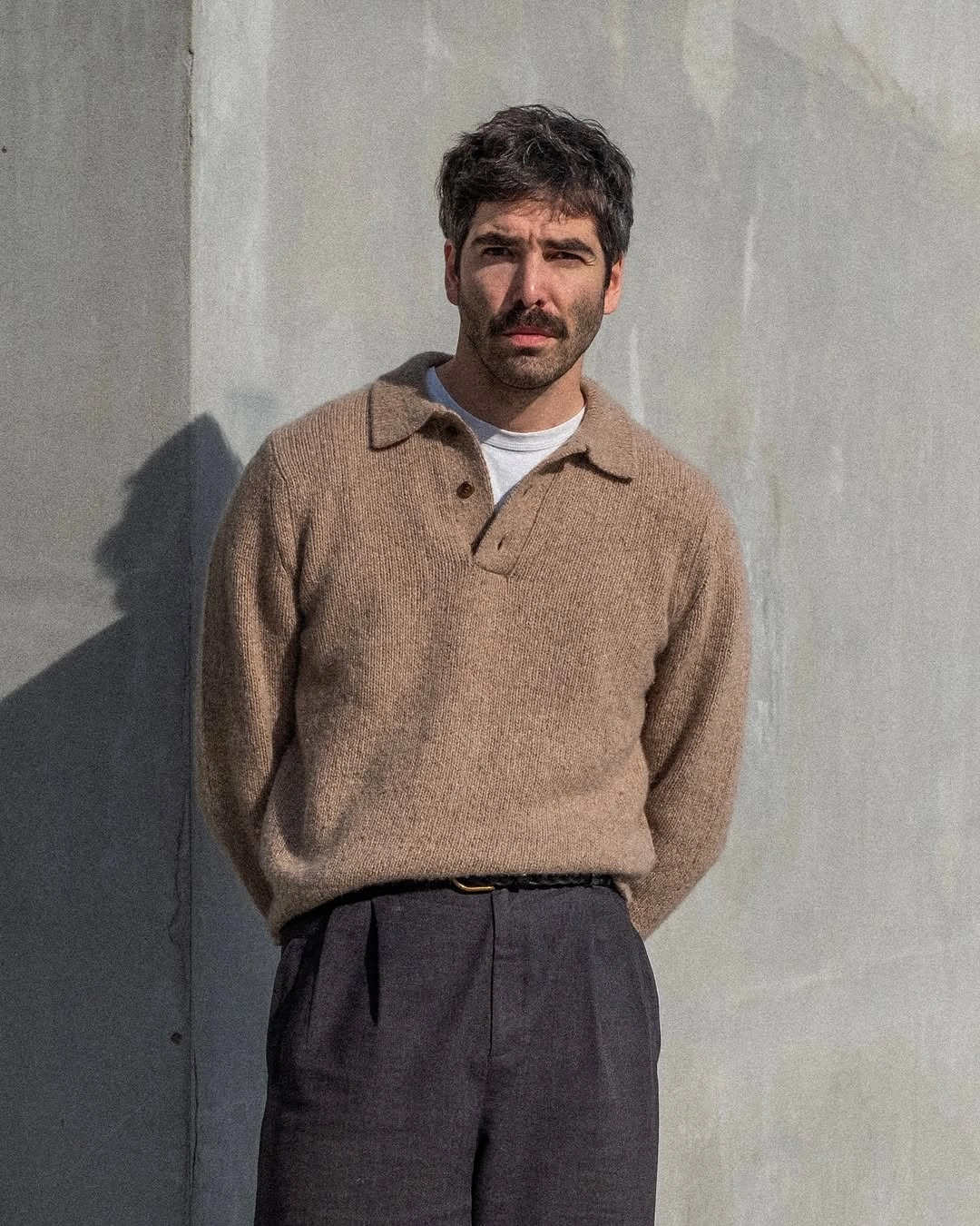 Brown knit polo with pleated charcoal trousers in a relaxed silhouette