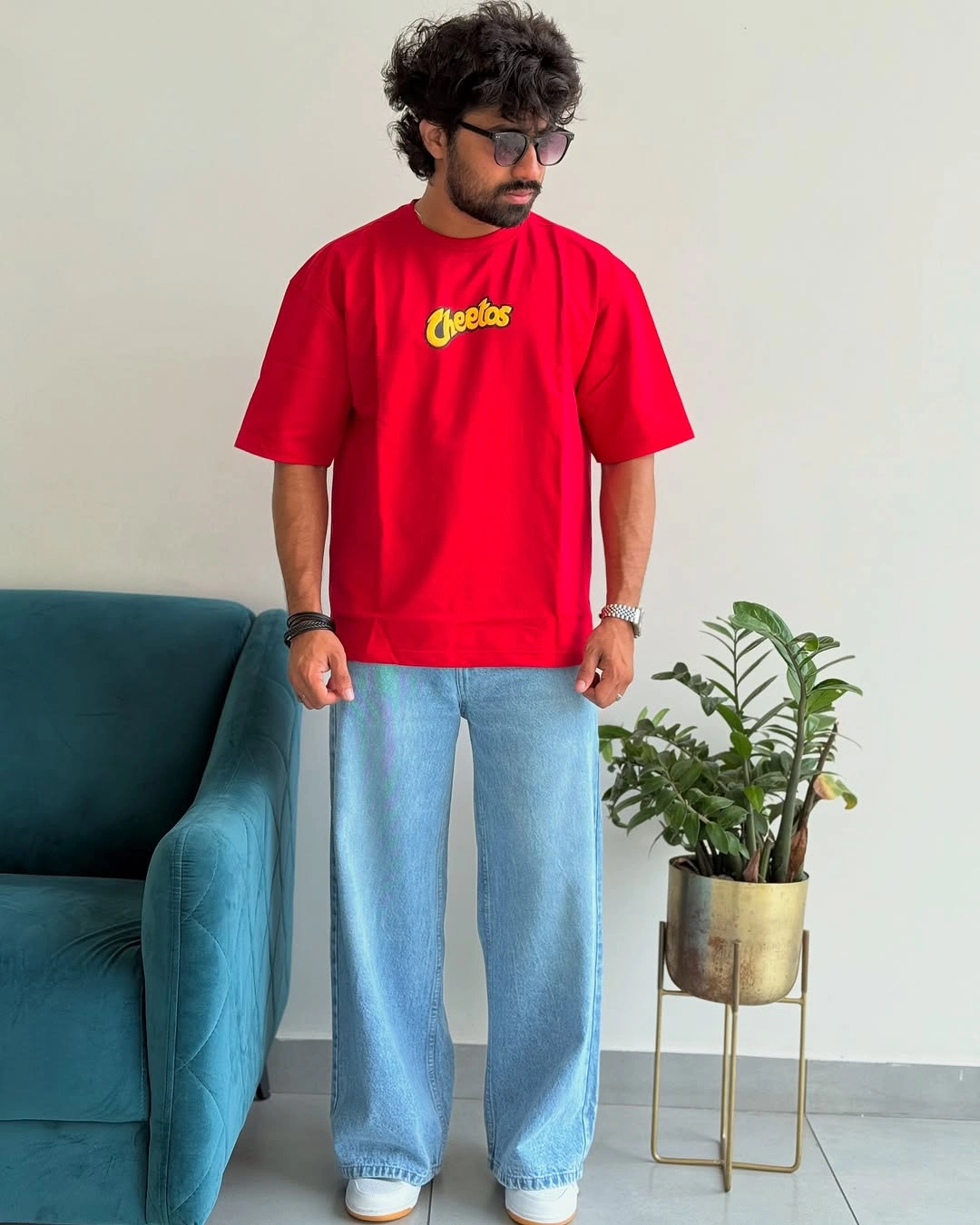 Bright red graphic T-shirt with wide pale blue jeans and white sneakers