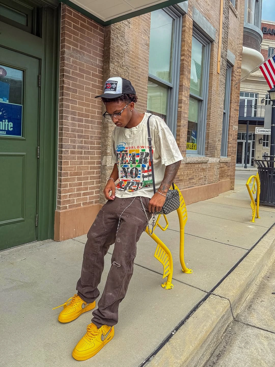 Graphic T-shirt brown trousers yellow sneakers and crossbody bag