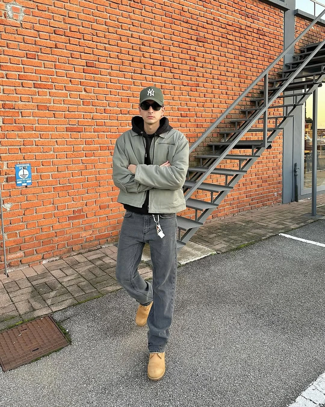 Olive jacket gray jeans tan boots and dark cap