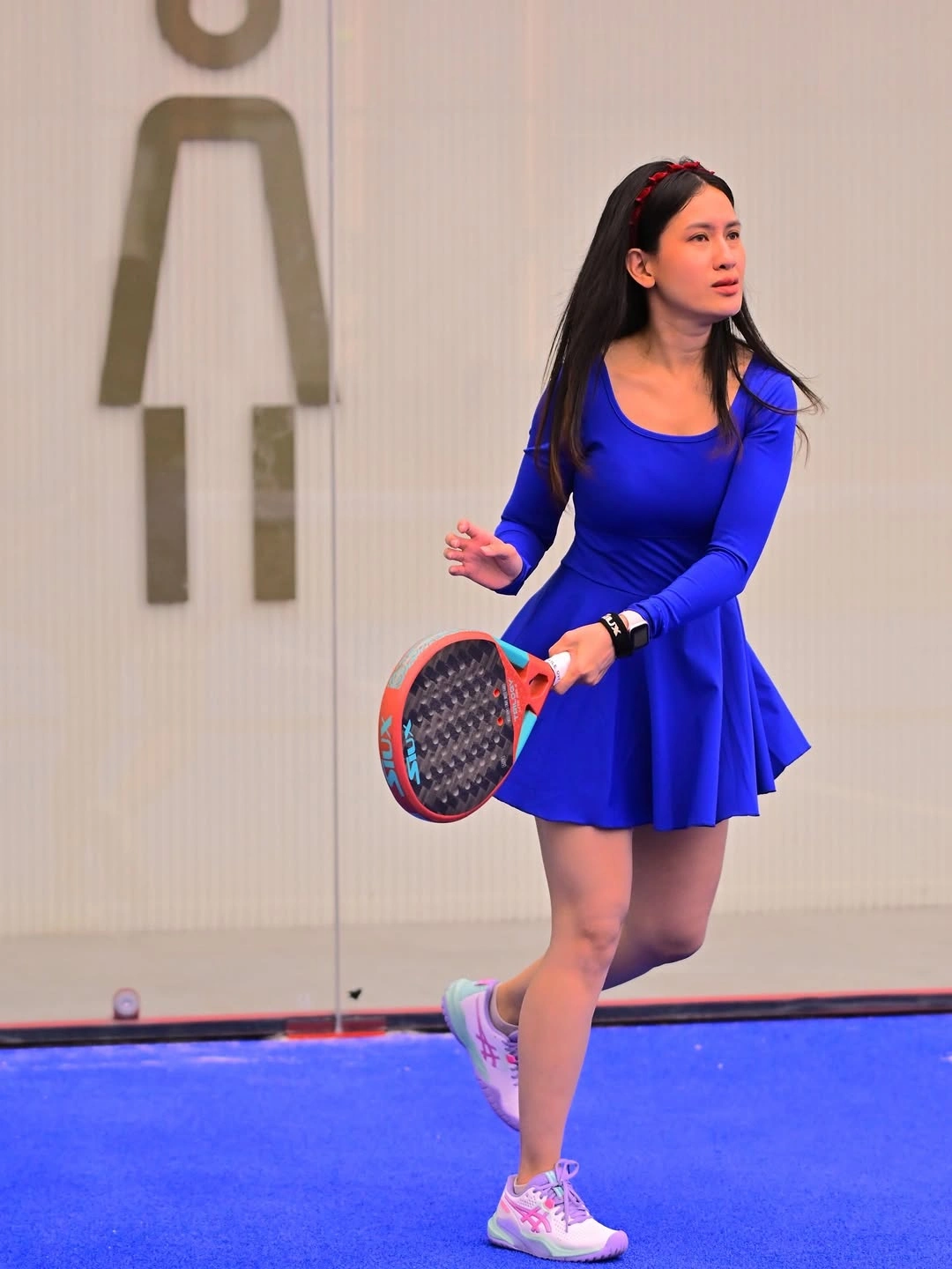 Cobalt long-sleeve athletic dress with white sneakers and padel racket