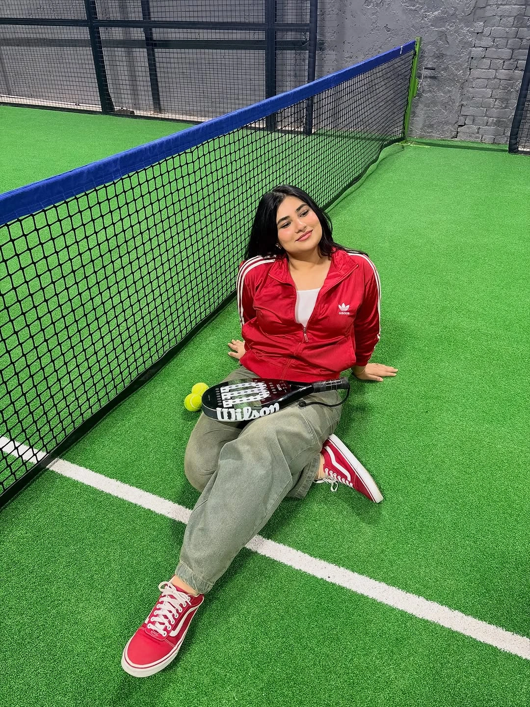 Red zip jacket gray loose pants and padel racket