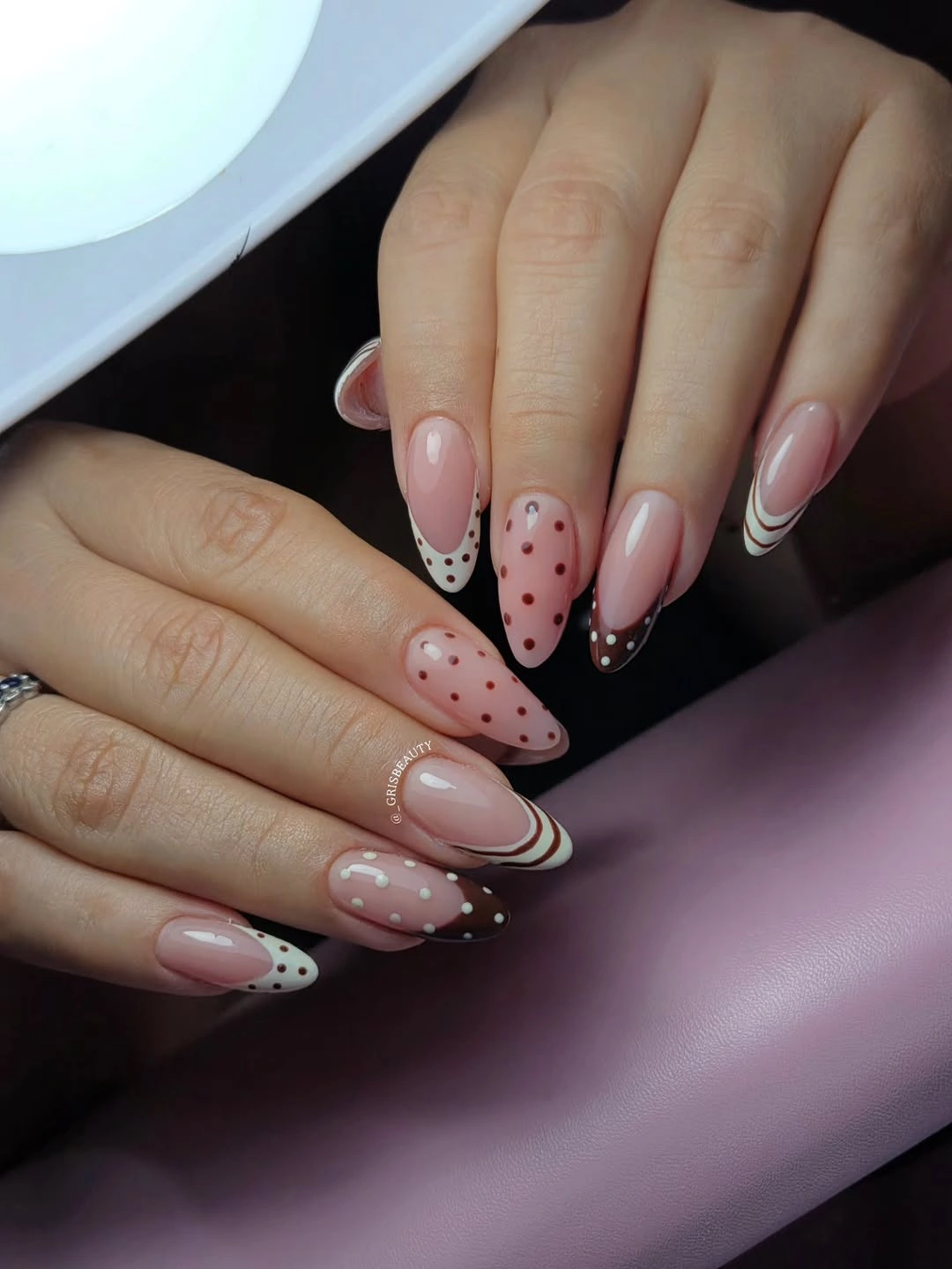 Pale pink nails with black white dotted tips, black polka-dot accents, and bold curved black edge