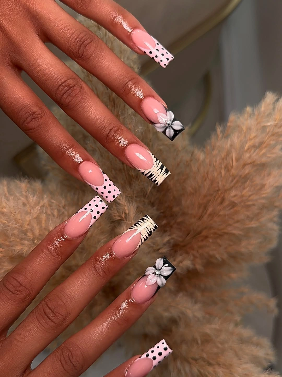 Long pink nails with black dotted tips, fine white line accents, and black white floral detail