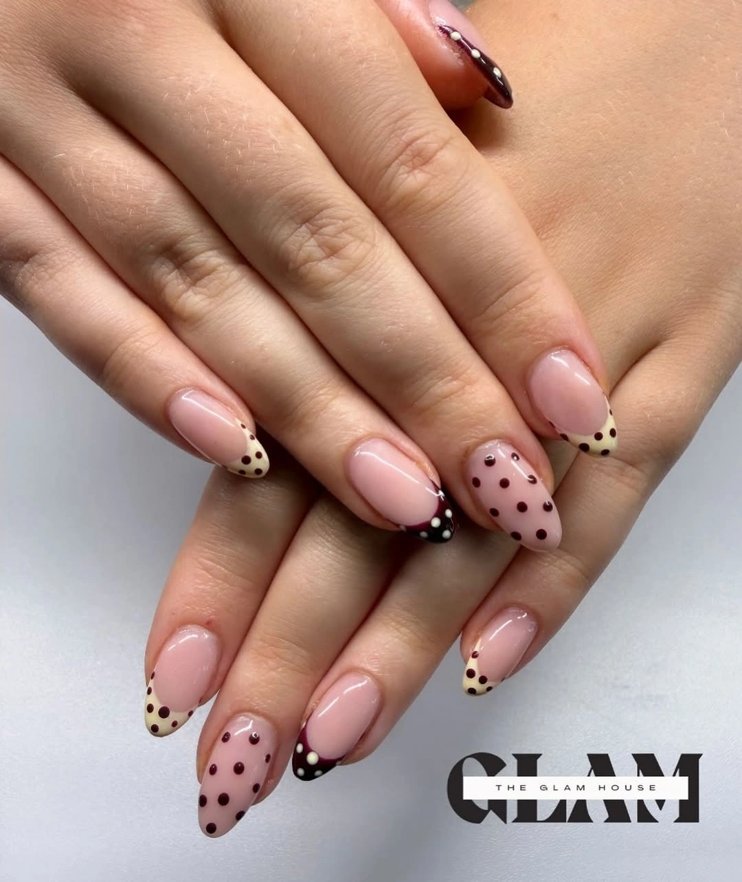 Pale pink almond nails with black dotted French-style tips and soft mauve accent