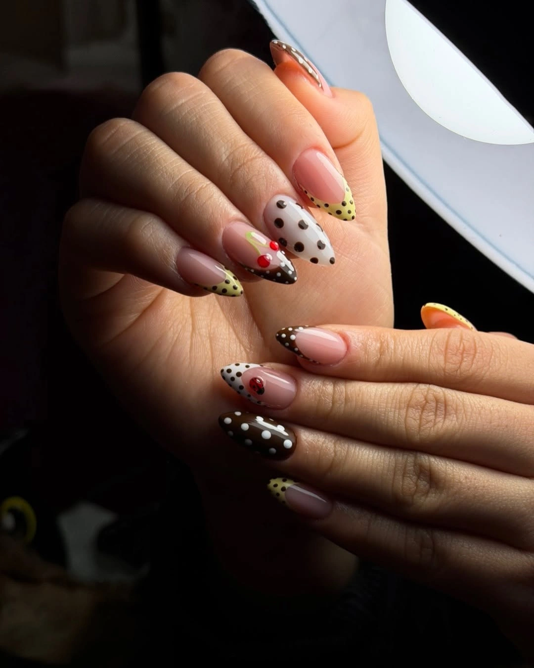 Short pale pink nails with red dots near tips and curved red French-style edges
