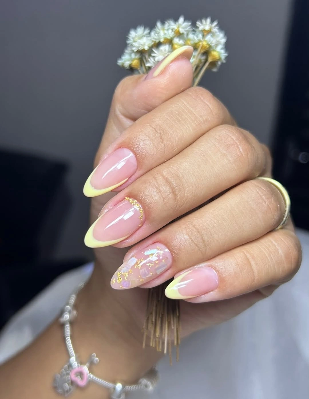 Longer almond nails with yellow tips and gold-toned accents