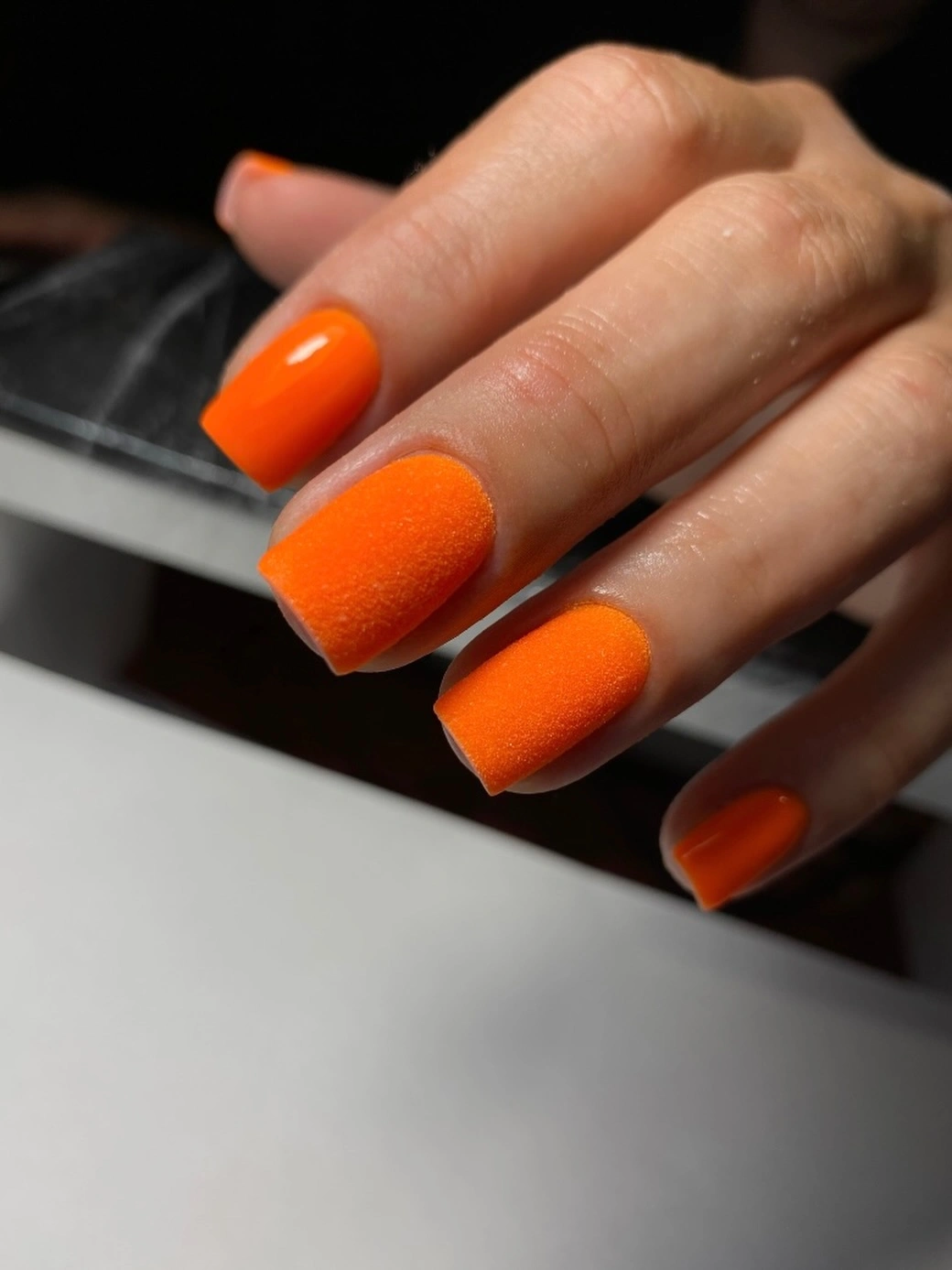Short squared orange nails with glossy and textured finishes