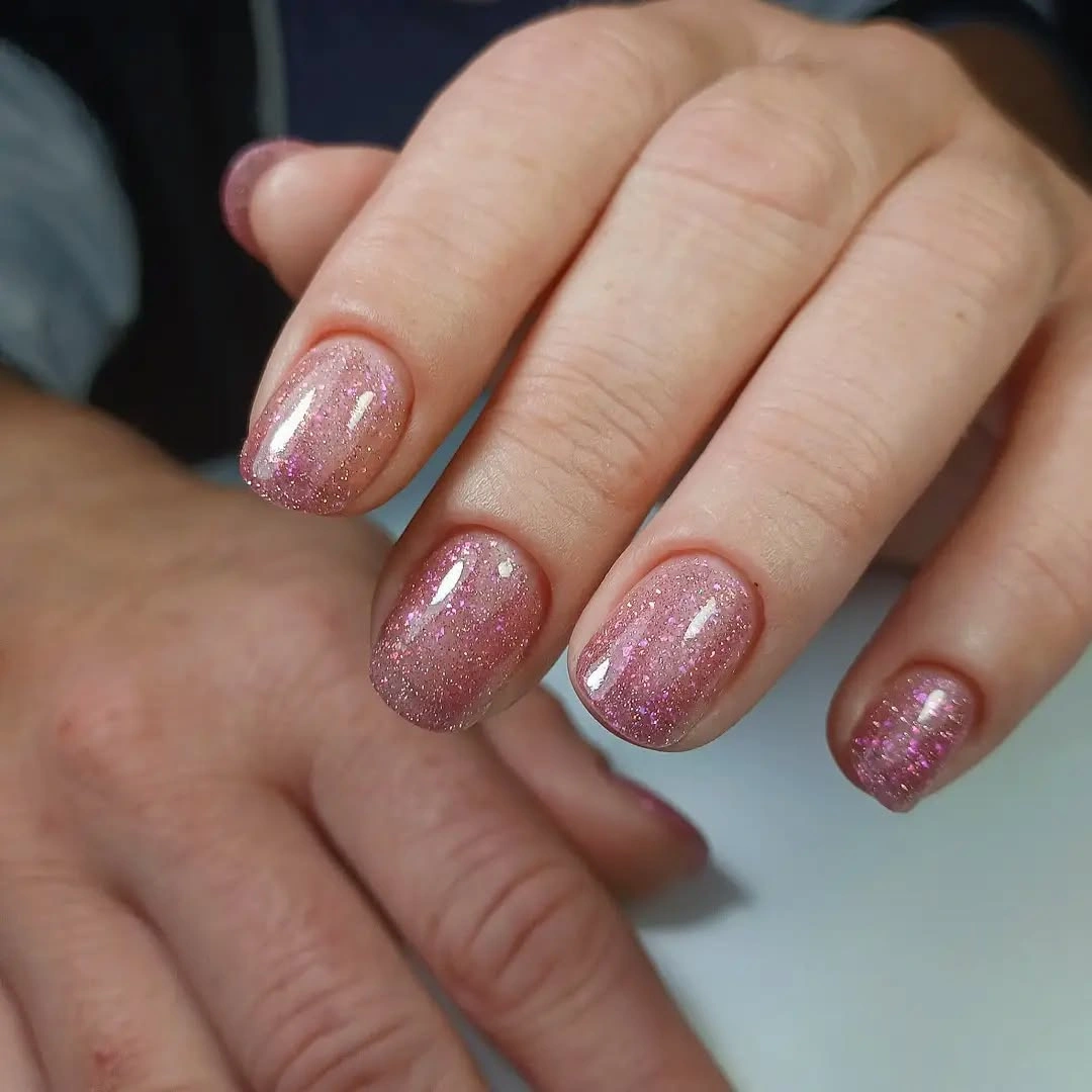 Very short rounded nails with sheer pink sparkle
