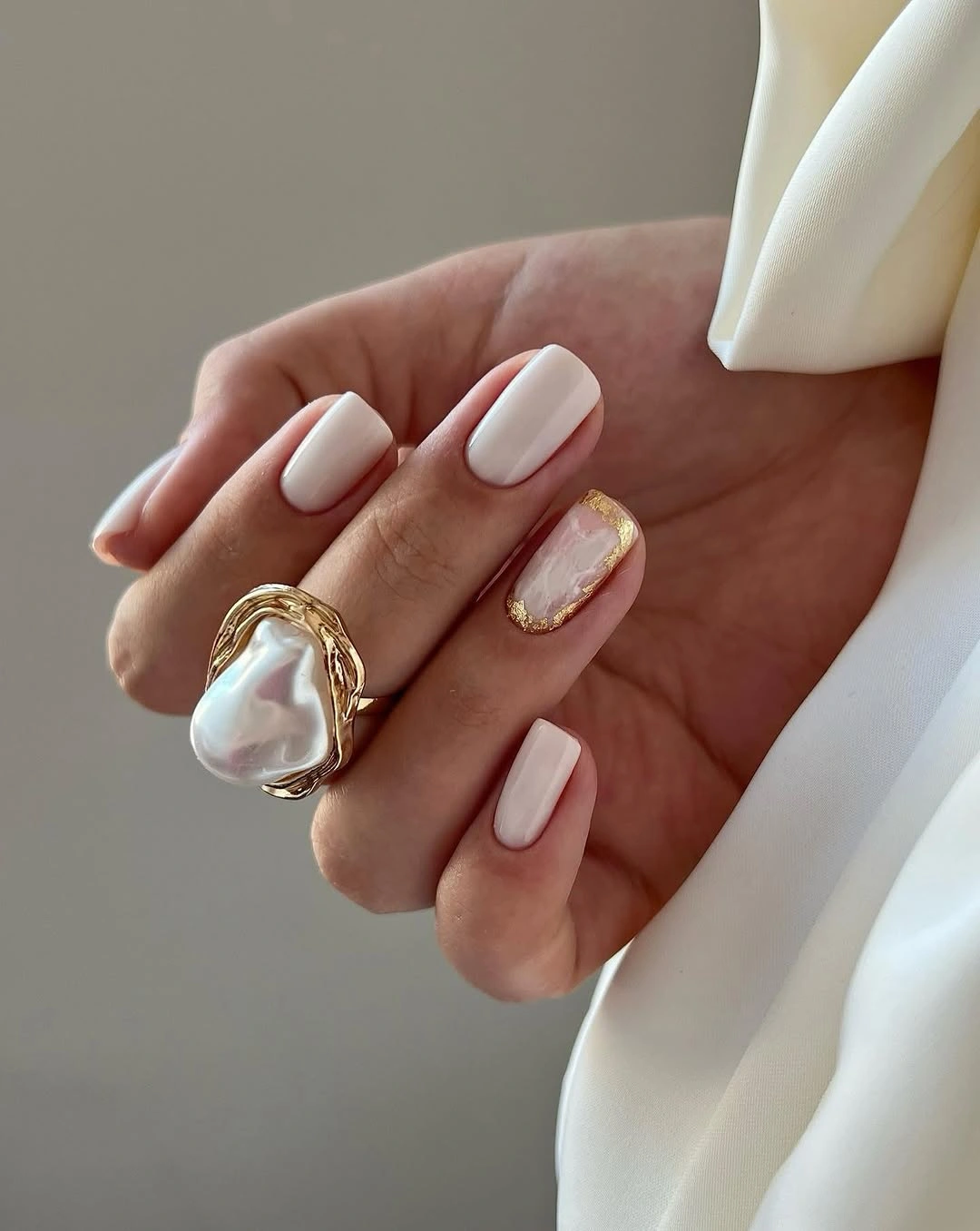 Milky rounded nails with one gold-framed accent