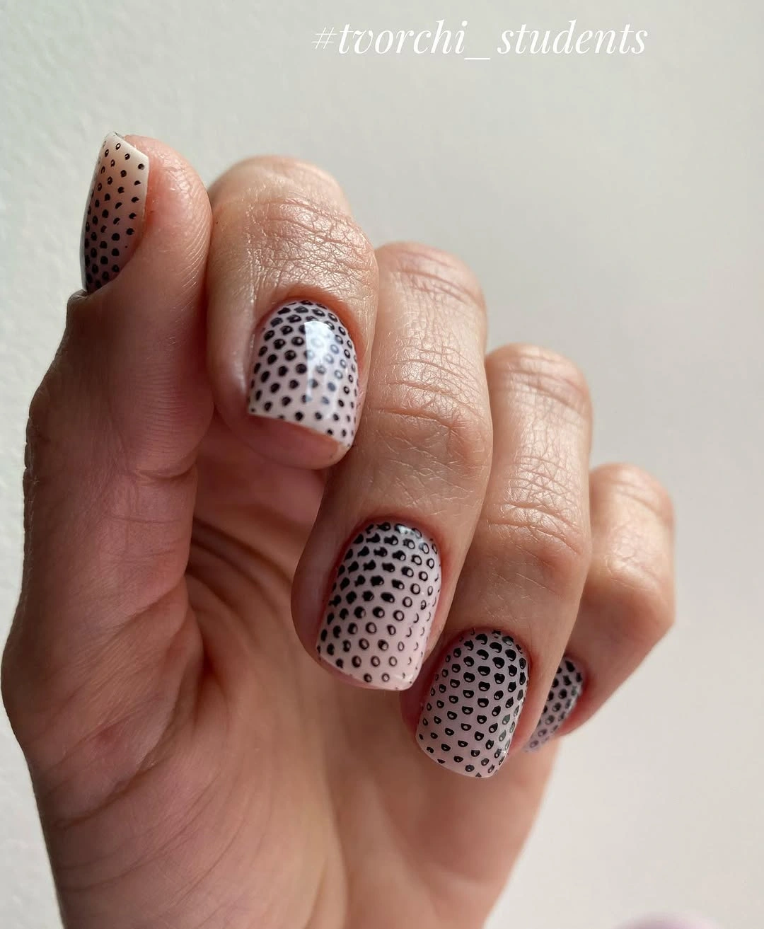 Short rounded nails with pale bases and tiny black dots