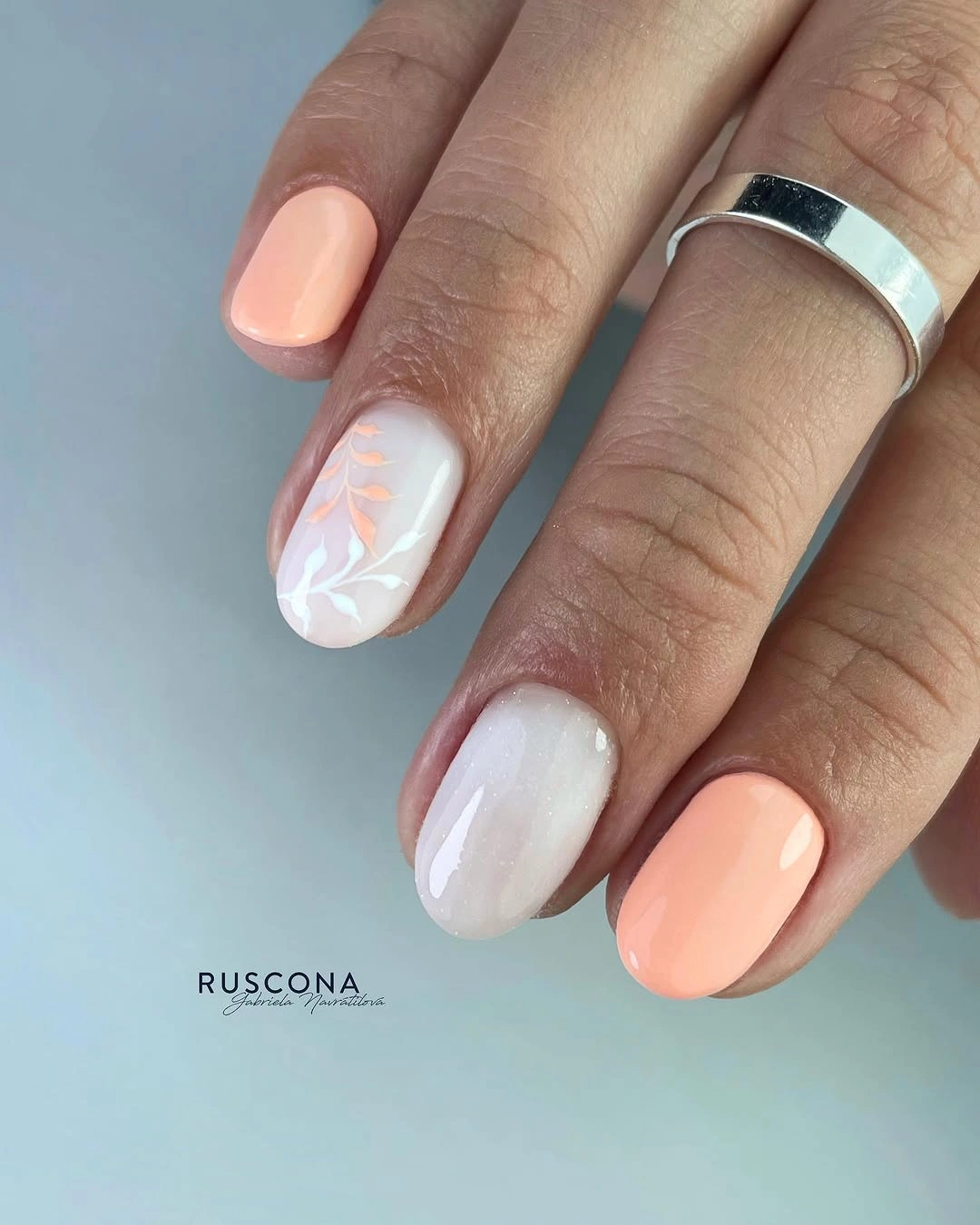 Short peach and milky white nails with leaf accent