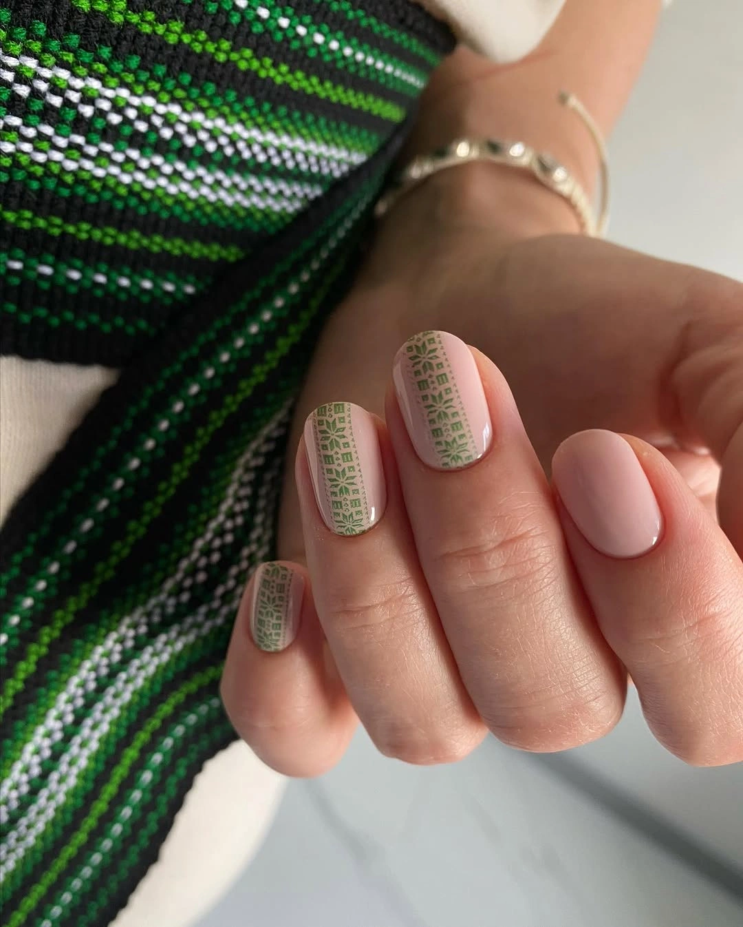 Short rounded nails with green grid pattern and pale pink polish