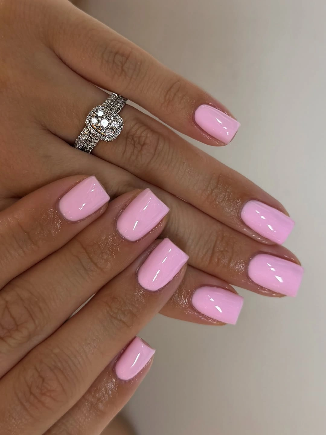 Glossy pale pink square nails on crossed hands