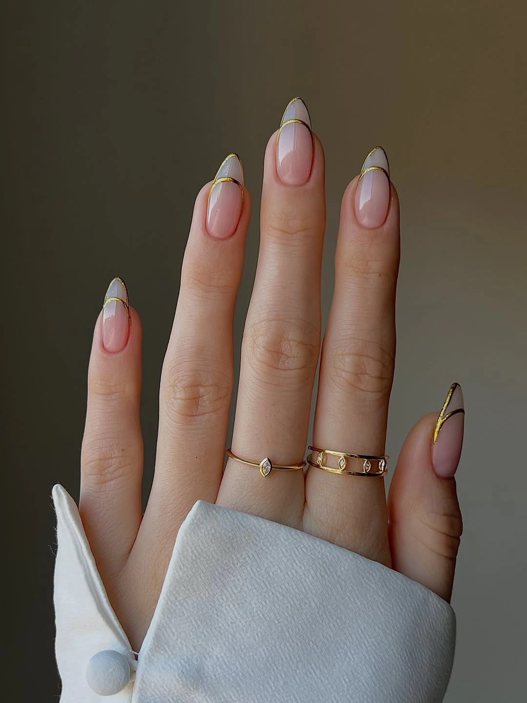 Longer almond nails with sheer bases and gold linework