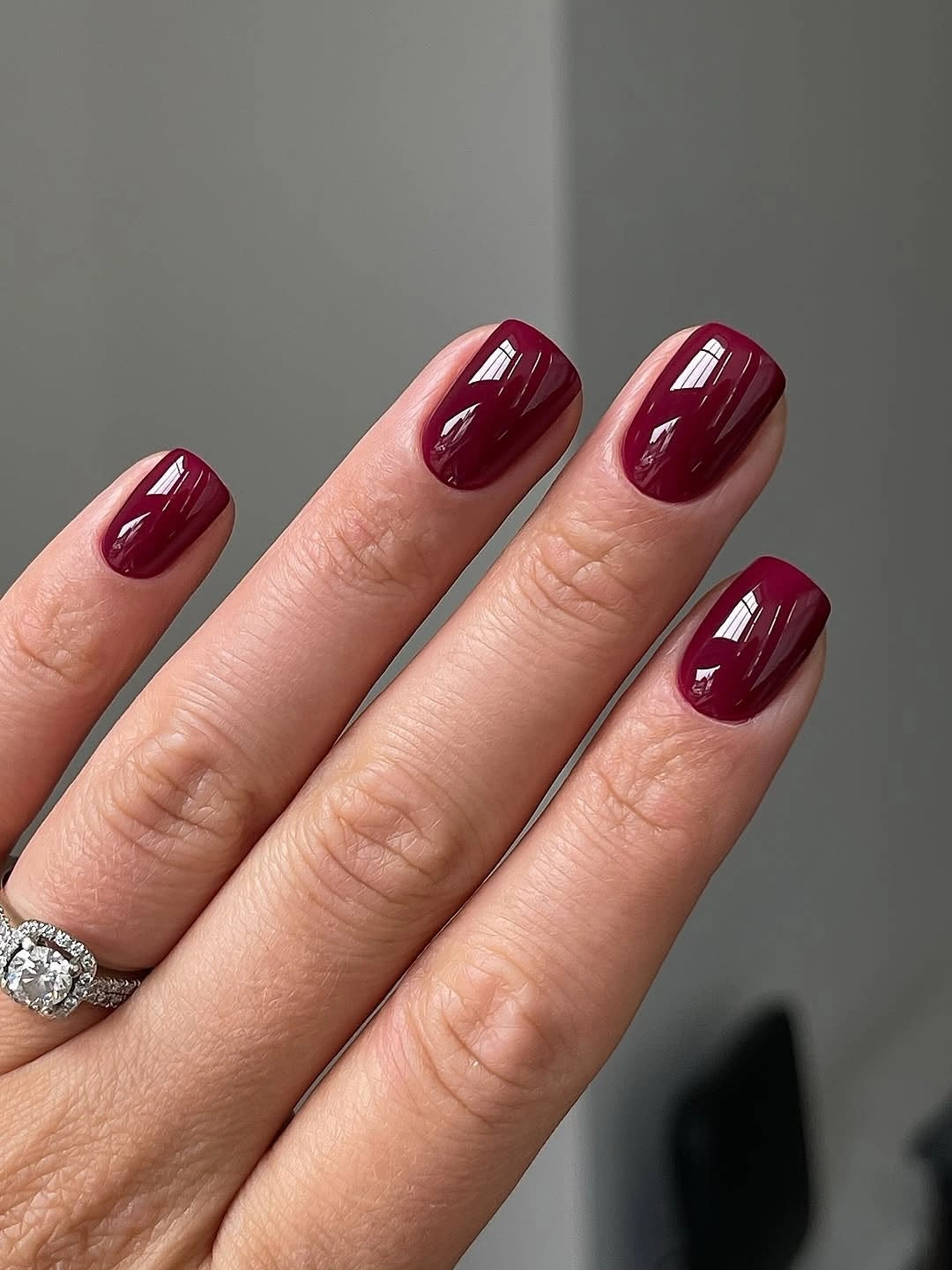 Short rounded nails with glossy deep burgundy polish