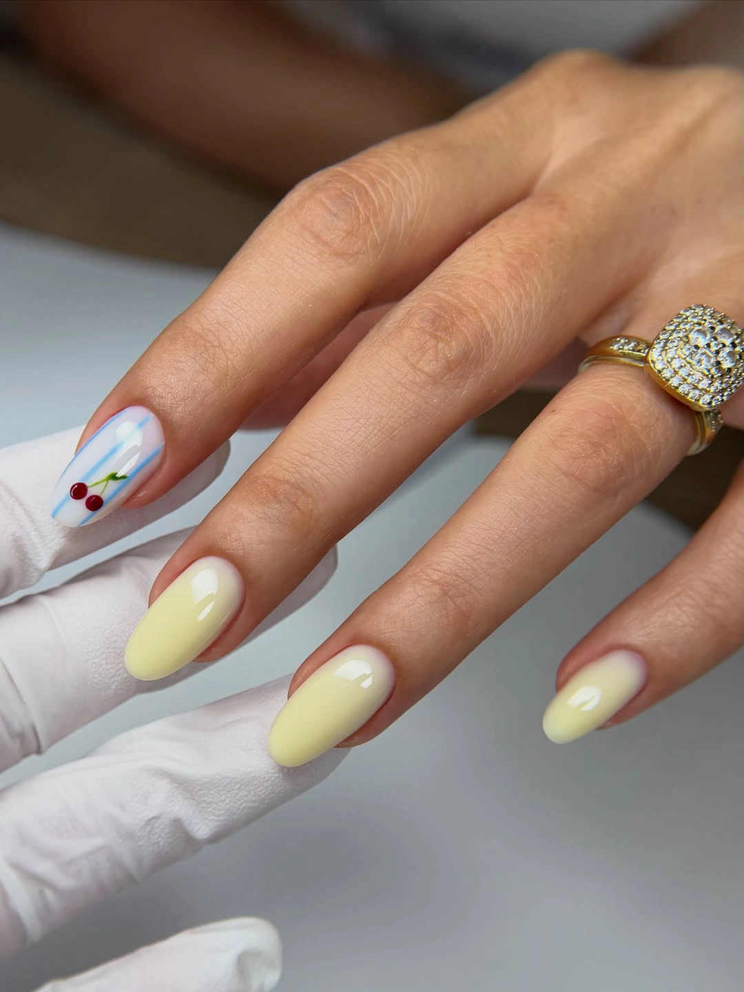 Pale yellow rounded nails with small cherry accent art