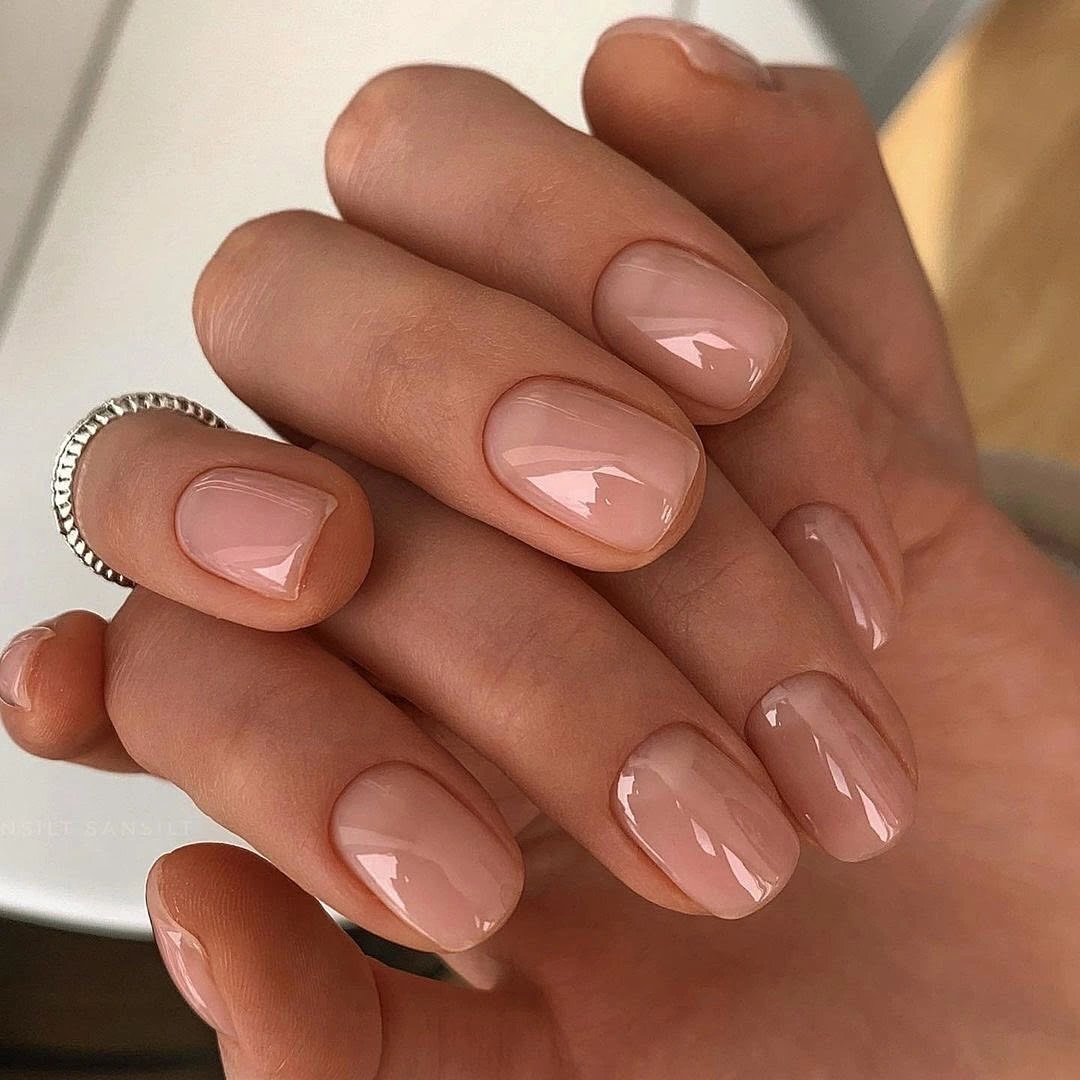 Very short rounded nails with glossy sheer nude polish