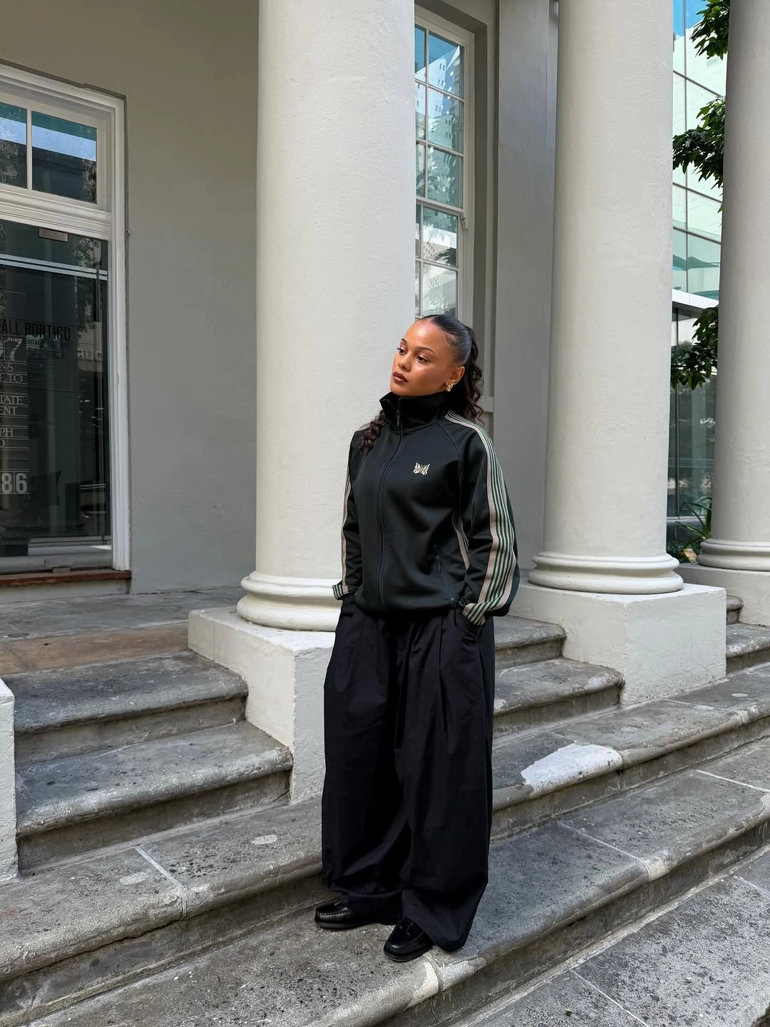 Black striped track jacket with extremely wide black trousers and dark shoes