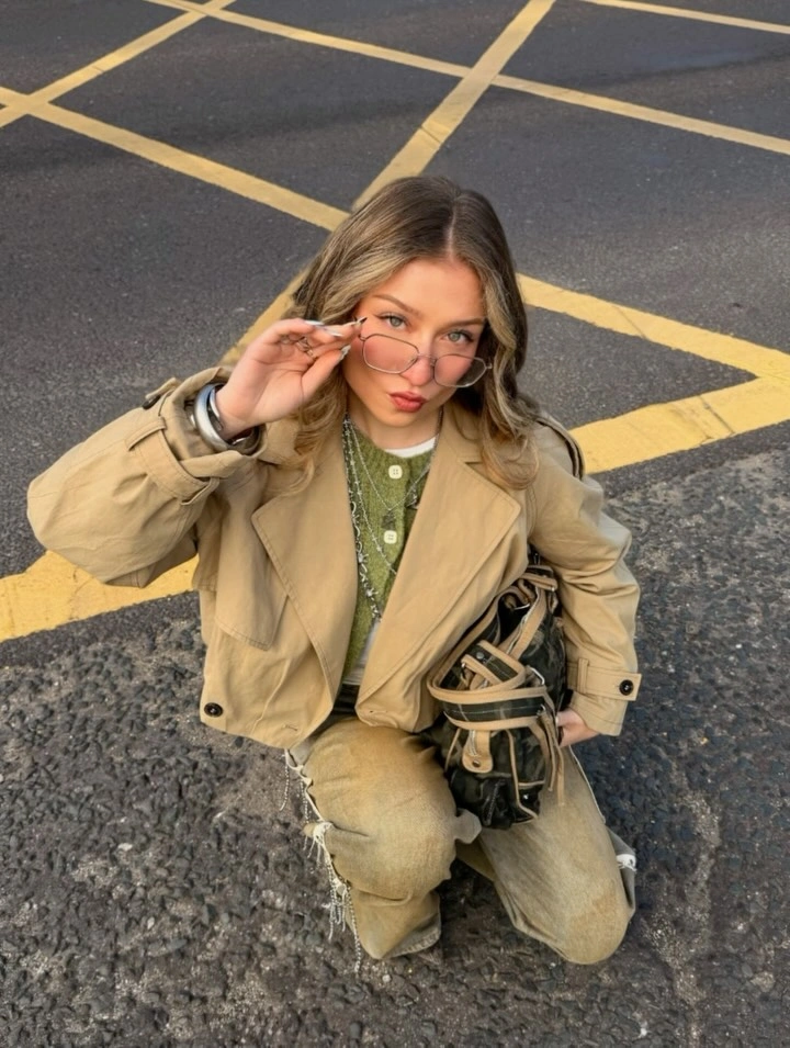 Tan utility jacket and cargo trousers with muted green top, tinted glasses, and black belt bag