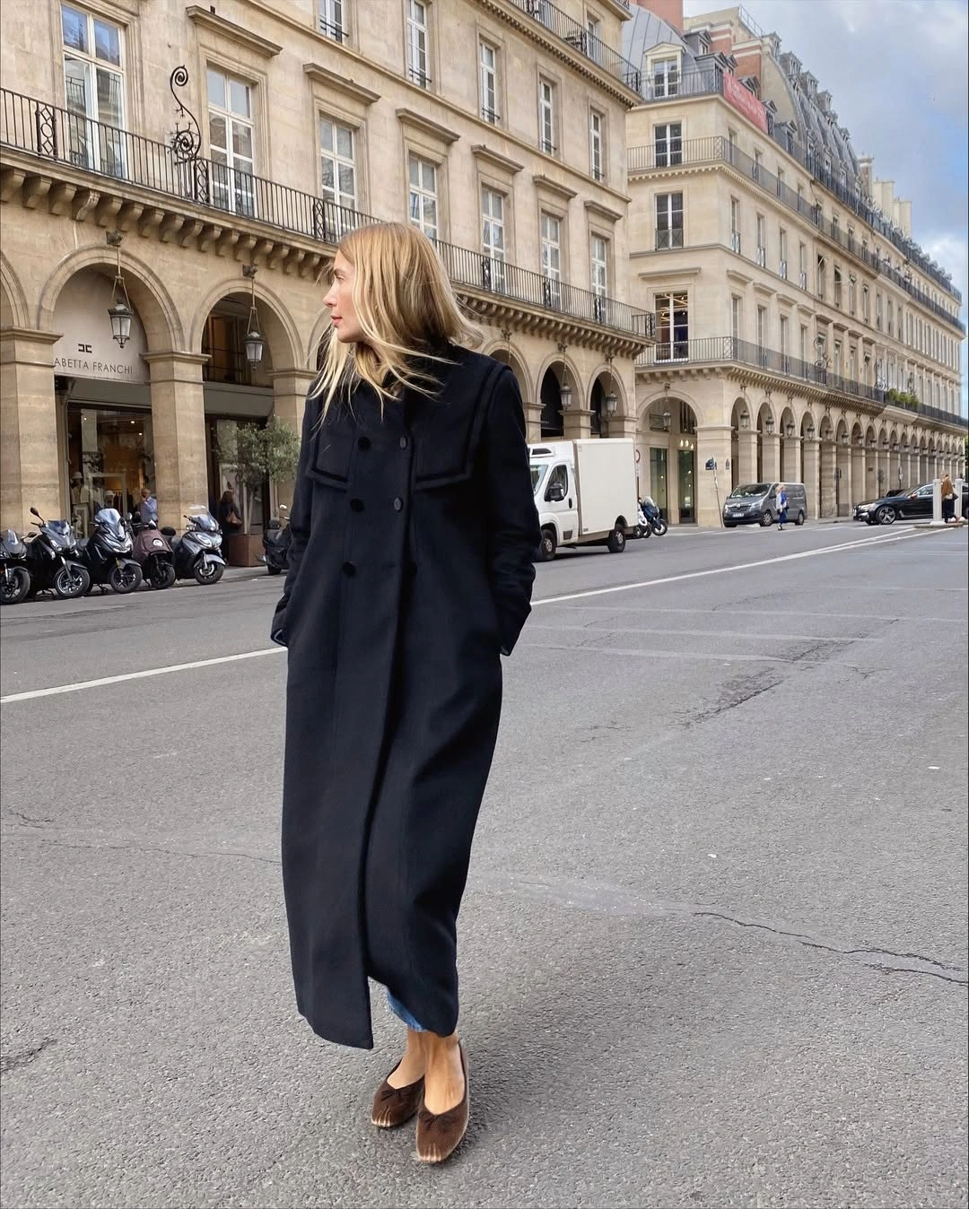 Long dark buttoned coat worn with brown pointed shoes