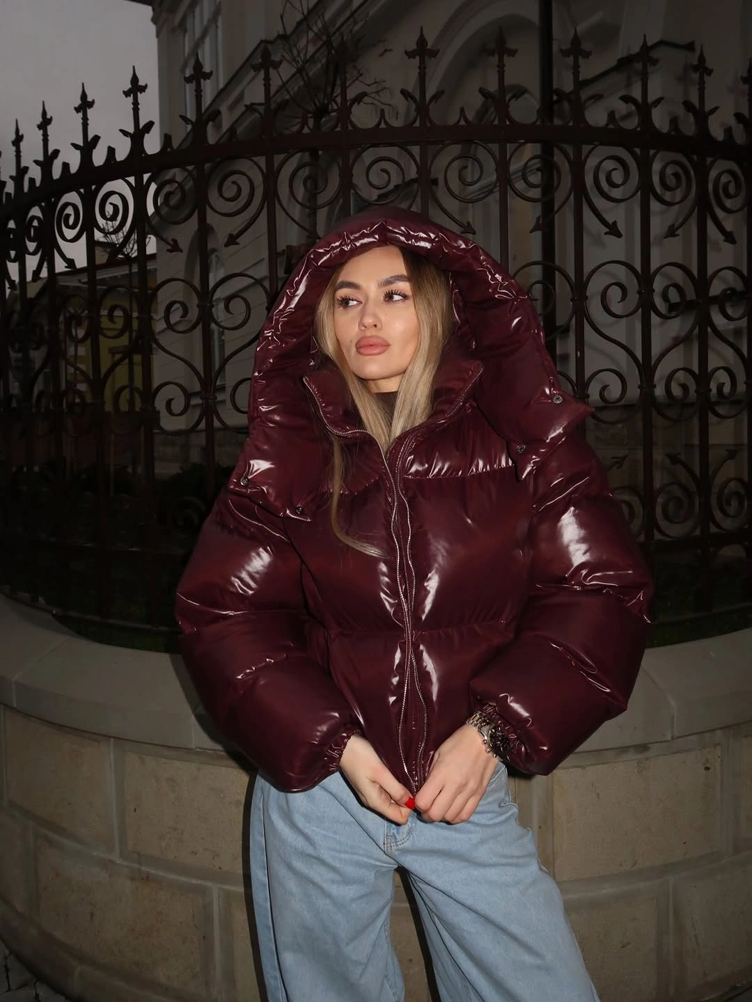 Glossy burgundy hooded puffer with light blue jeans