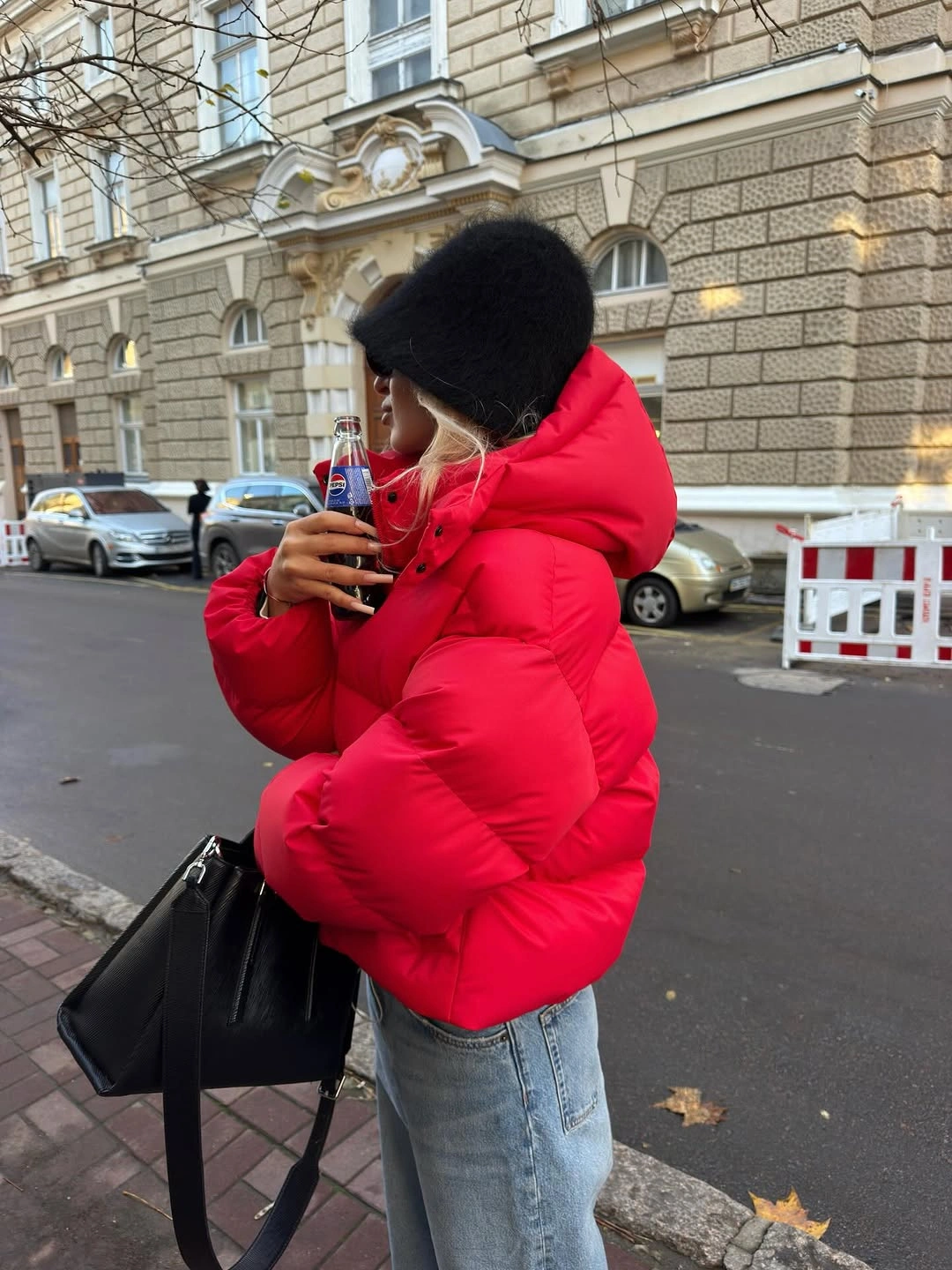 Bright red cropped puffer with black hat and jeans